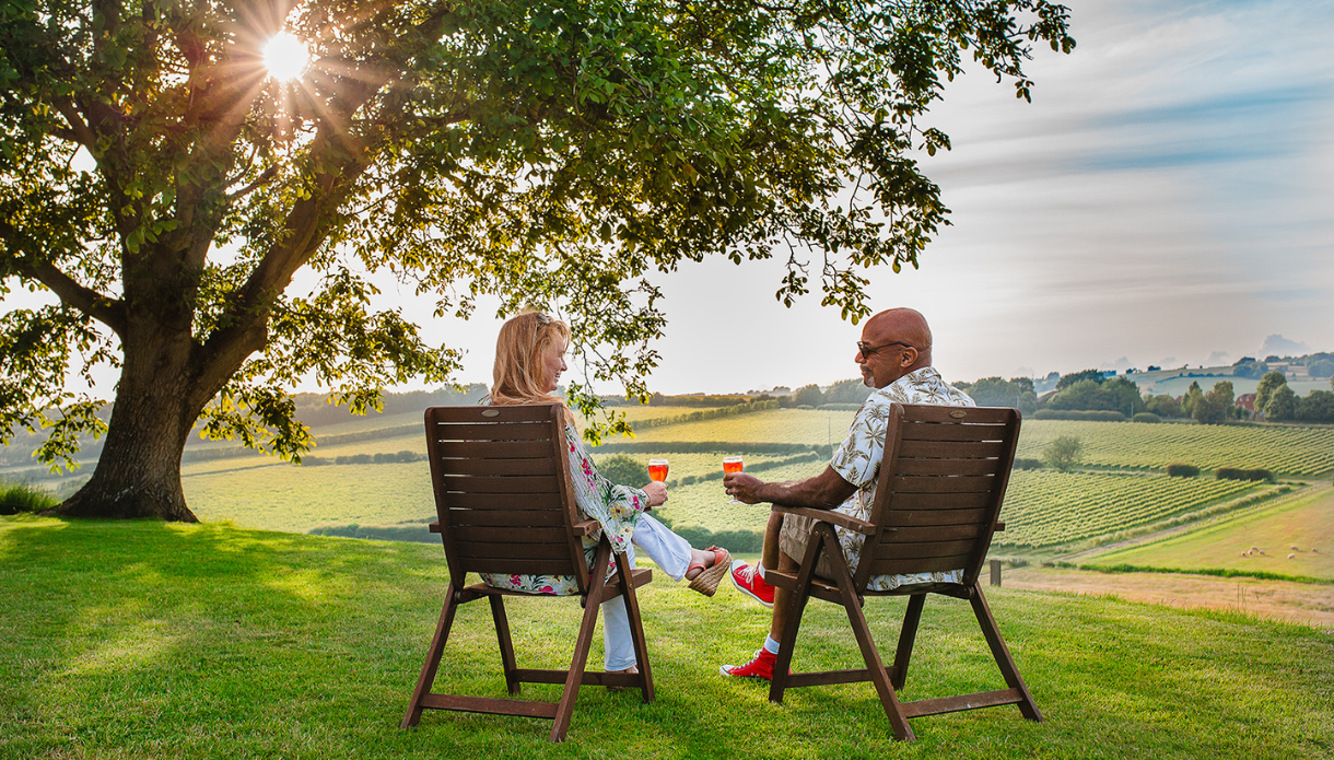 Image shows a couple sitting at Charles Palmer Vineyard with the background of the rolling valleys and vineyard. Image shows a couple sitting at Charles Palmer Vineyard with the background of the rolling valleys and vineyard.